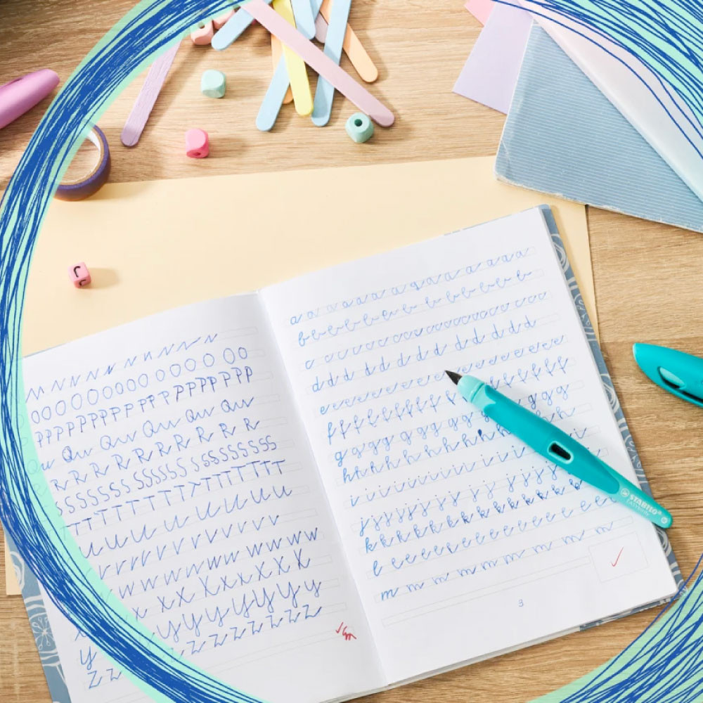 STABILO ergonomischer Schulfüller EASYbirdy pastell aqua grün/mint liegt auf Deutschheft